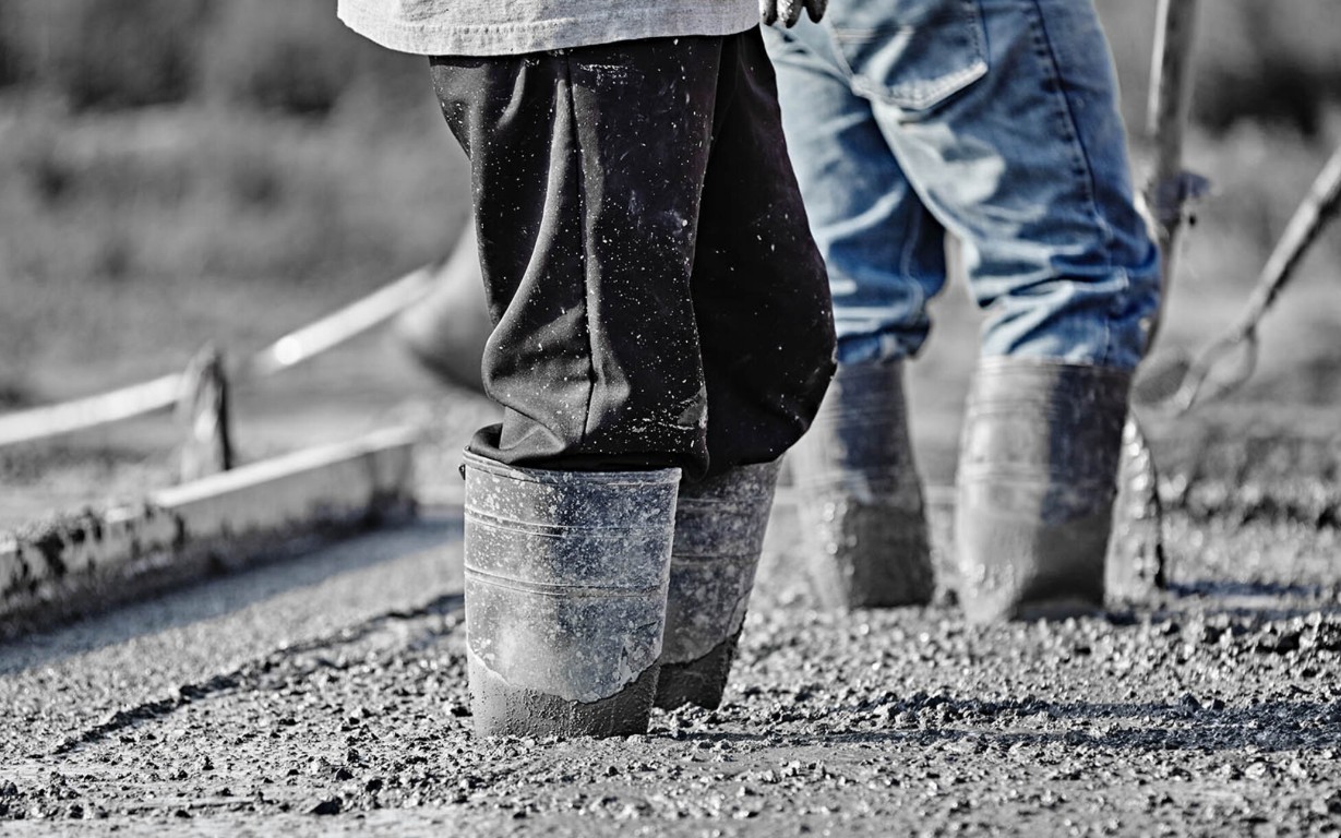 Concrete workers pouring wet concrete for a pool deck in Laredo, TX